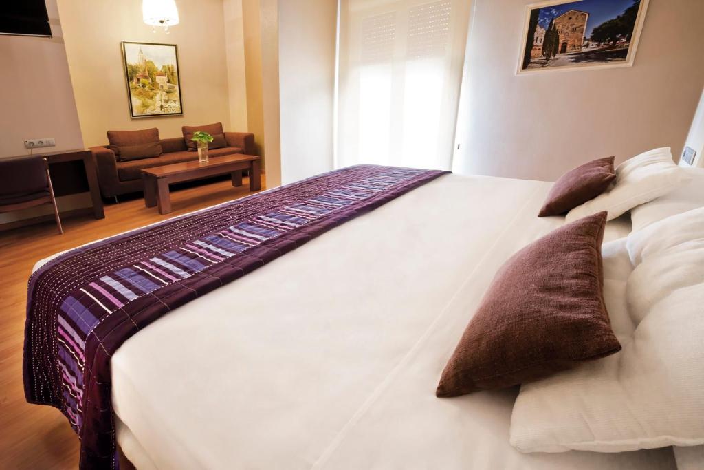 een slaapkamer met een groot wit bed met kussens bij Hotel Fuente El Cura in Sax