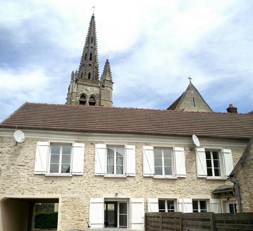 un ancien bâtiment en pierre avec une église en arrière-plan dans l'établissement Les Fontaines, à Baron