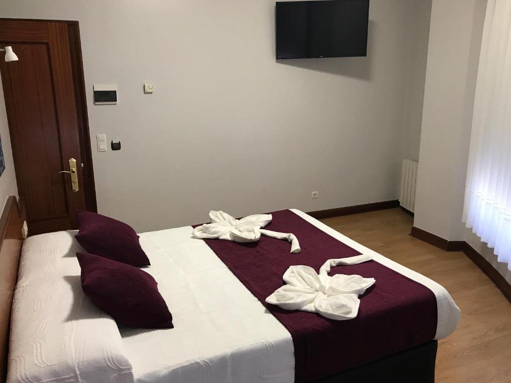Un dormitorio con una cama con dos flores blancas. en Pensión La Salve, en Bilbao