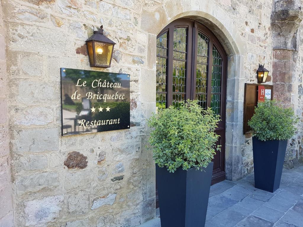 un bâtiment avec deux plantes en pot devant une porte dans l'établissement L'Hostellerie du Château de Bricquebec, à Bricquebec