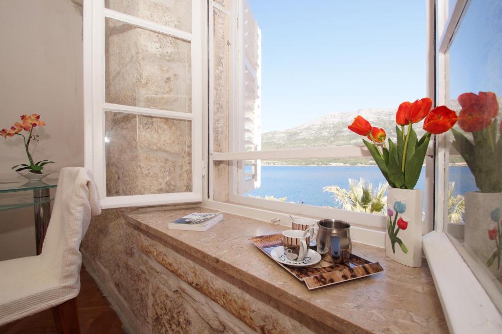 Una habitación con una ventana con flores en un mostrador en Guest House Holiday, en Korčula