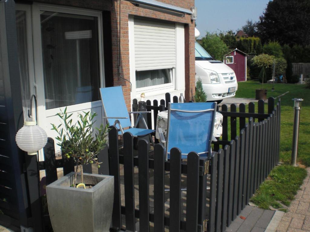 ブットヤーディンゲンにあるFerienwohnung Wittjeの家の前に青い椅子が2脚ある柵
