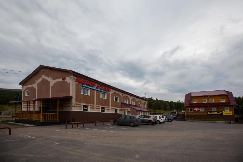 un edificio con coches estacionados en un estacionamiento en Nord Star Ski Complex, en Murmansk