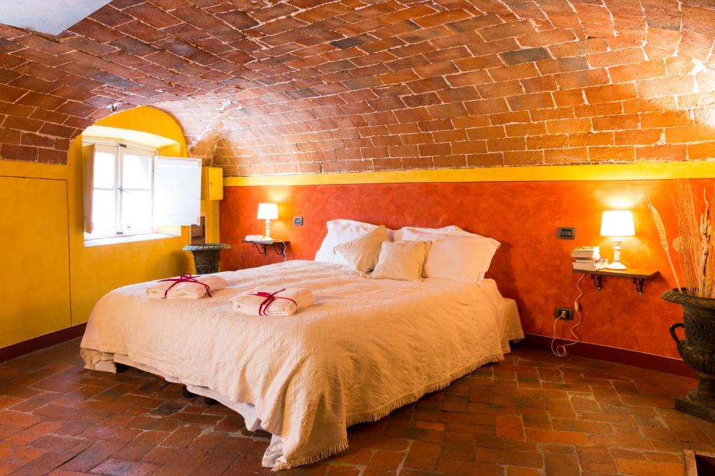 - une chambre avec un grand lit et un mur en briques dans l'établissement The Mezzanine within the Walls, à Lucques