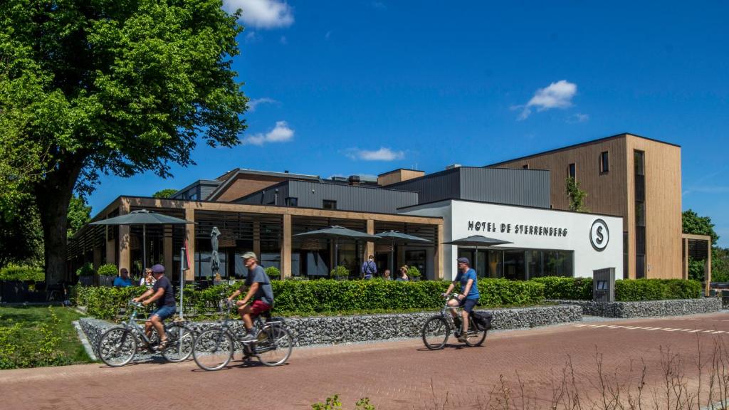 three people riding bikes in front of a building at Hotel de Sterrenberg - Adults Only in Otterlo