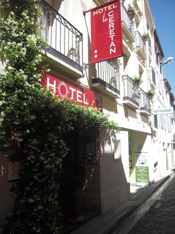 a hotel with red signs on the side of a building at Le Cérétan Hôtel in Céret