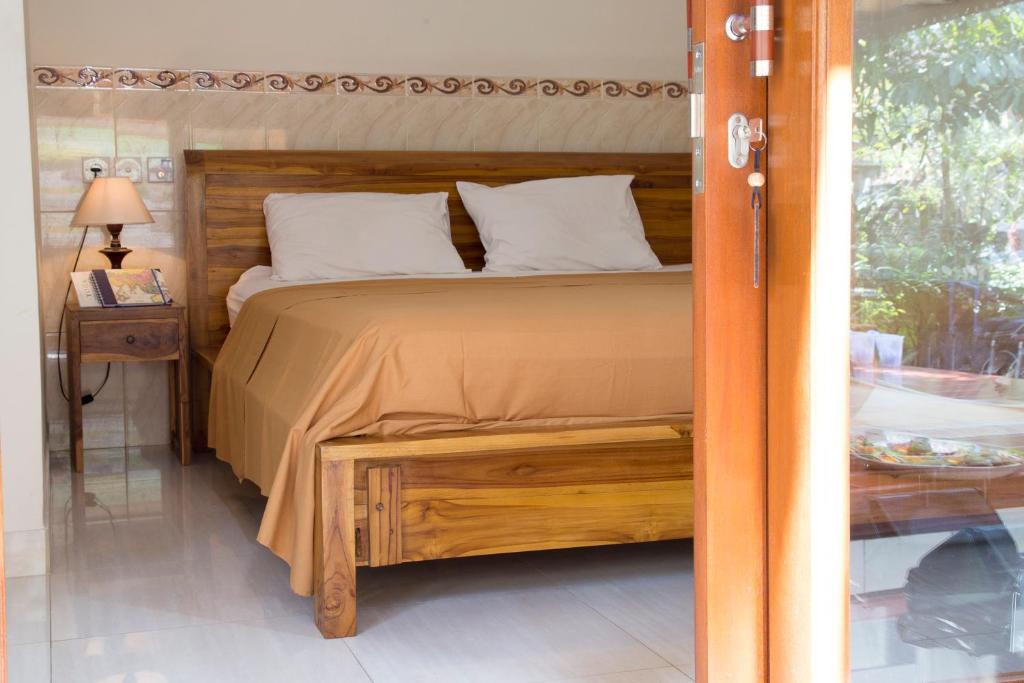 um quarto com uma cama e uma mesa com um candeeiro em CIK'S Guest House em Ubud