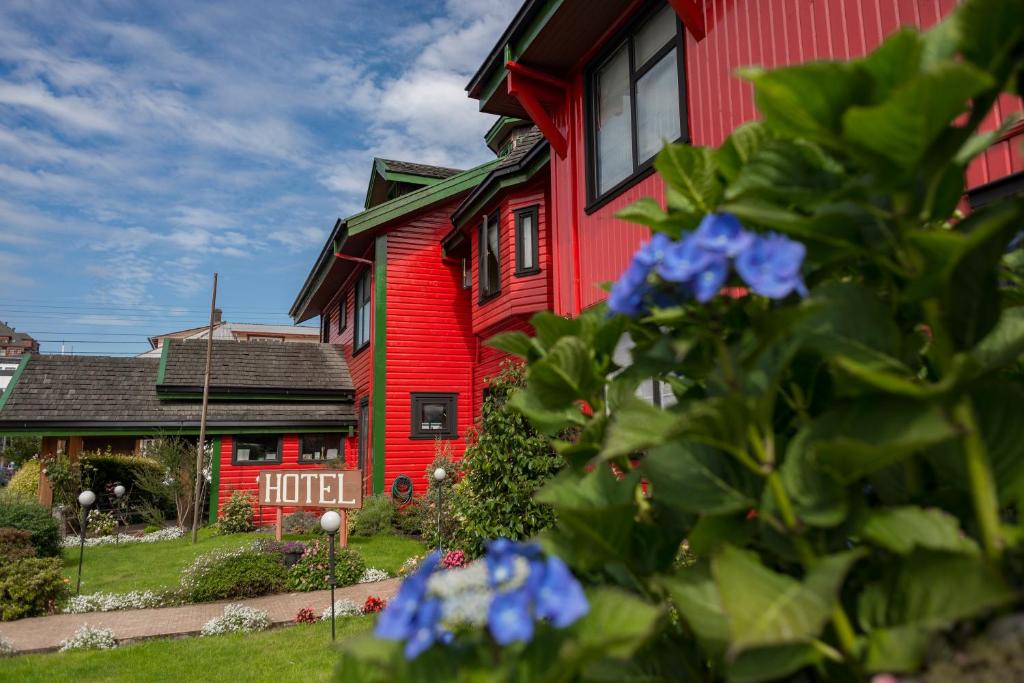 una casa roja con flores azules delante de ella en Weisserhaus, en Puerto Varas