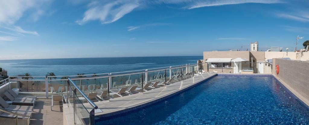 a swimming pool with chairs and the ocean in the background at Rosamar Maritim 4* in Lloret de Mar