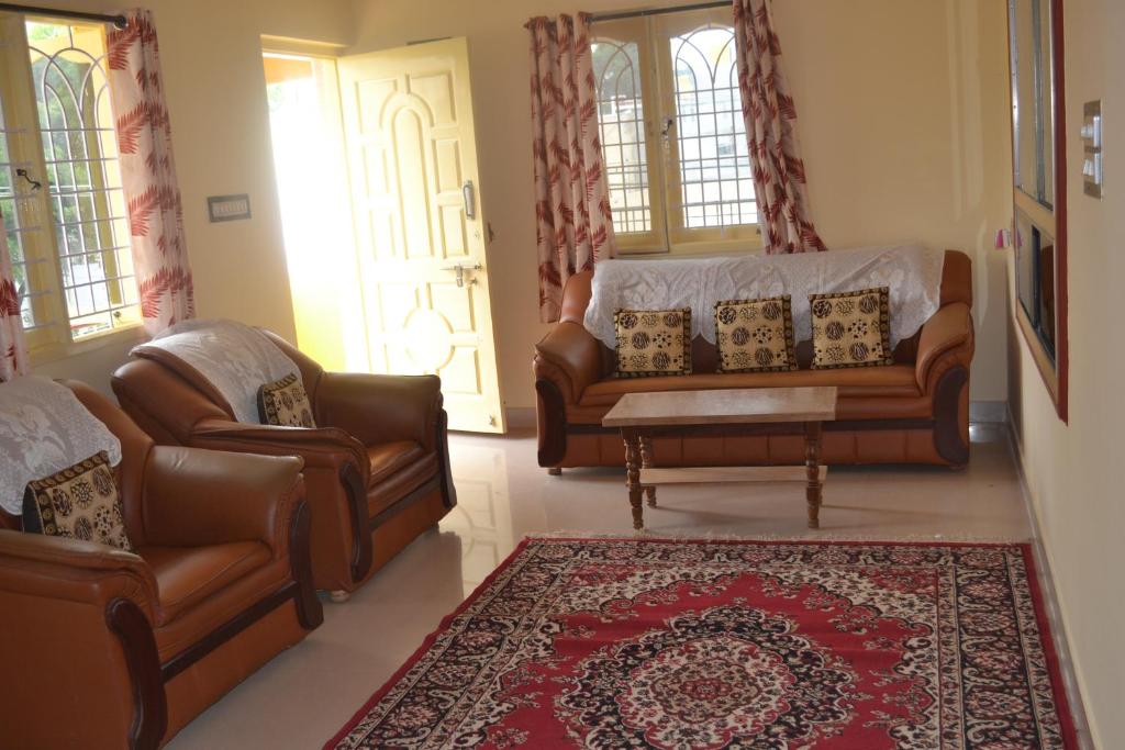 a living room with two leather couches and a rug at Manasvini Homestay-A home in Mysore with scenic view in Mysore