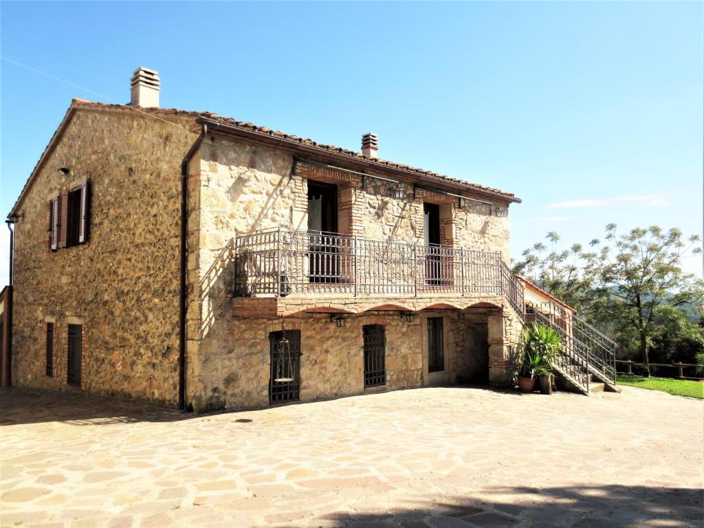 una antigua casa de piedra con un balcón en la parte superior. en Agriturismo L'Alba, en Roccastrada