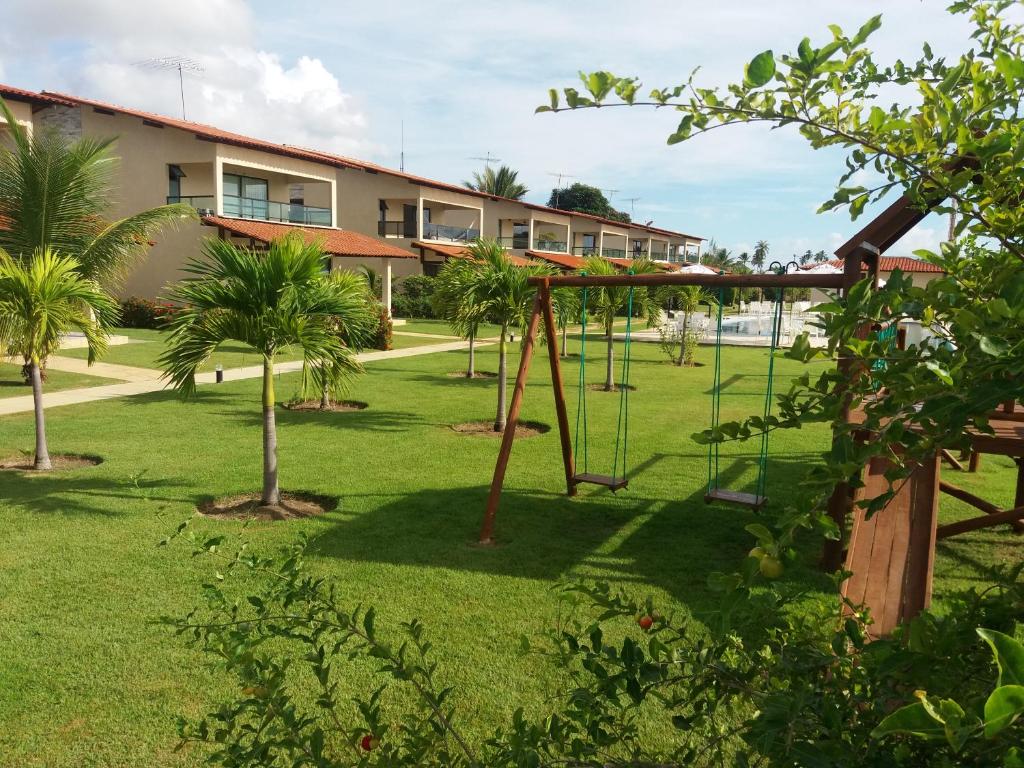 a playground in a park with palm trees and a building at Casa de Praia in Porto De Galinhas