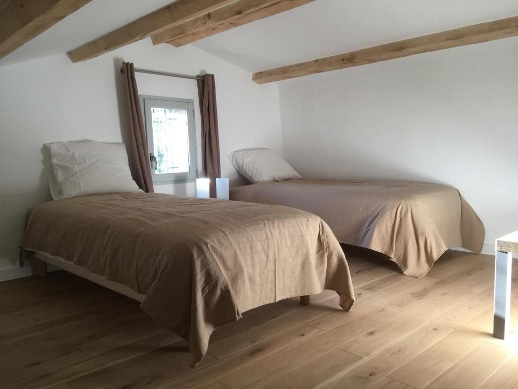 Duas camas num quarto com pisos em madeira em Gorges du Verdon charme et authenticite semaine du samedi au samedi en juillet et août em Bargème