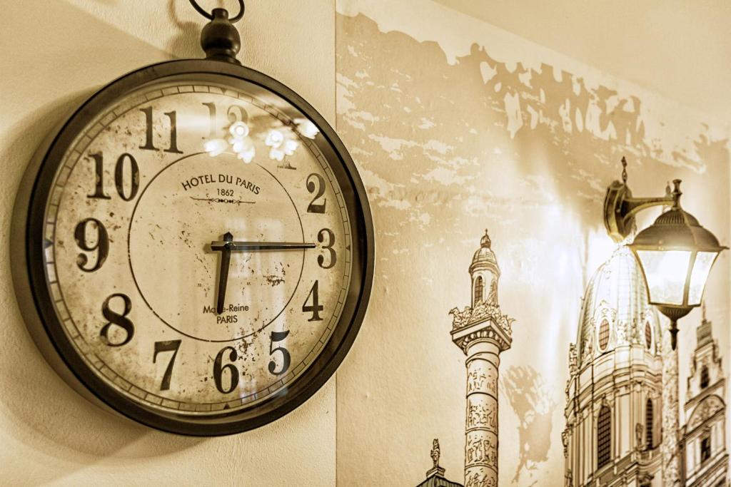 a clock hanging on a wall with a picture of a tower at Kepler Home in Vienna