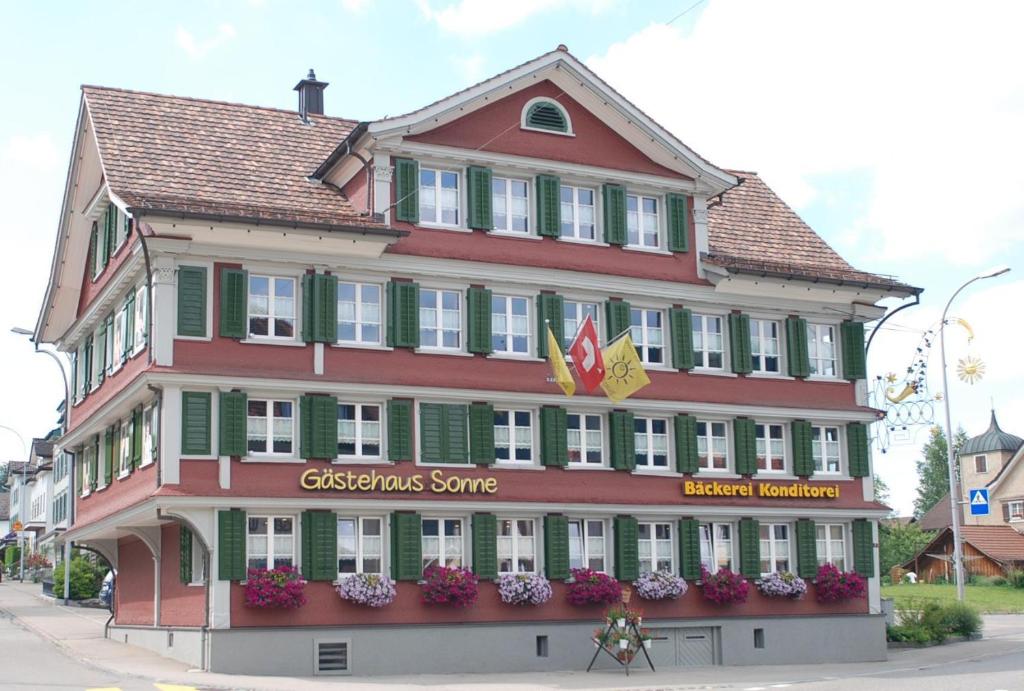 un grand bâtiment rouge avec un magasin de Noël dans une rue dans l'établissement Gästehaus Sonne, à Bütschwil