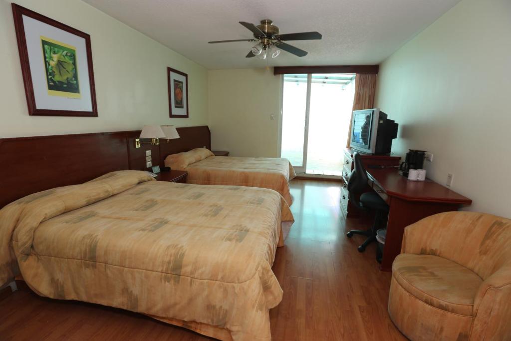 a hotel room with two beds and a television at Hotel Marcella Clase Ejecutiva in Morelia