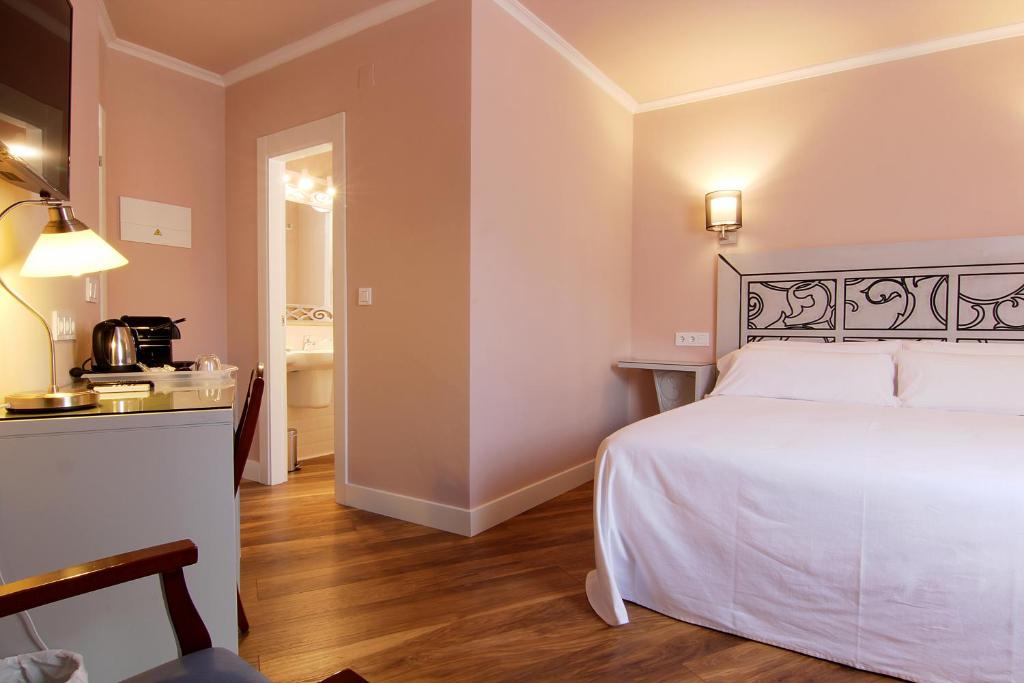 a bedroom with a white bed and a bathroom at Hostal Los Castañuelos in Candeleda