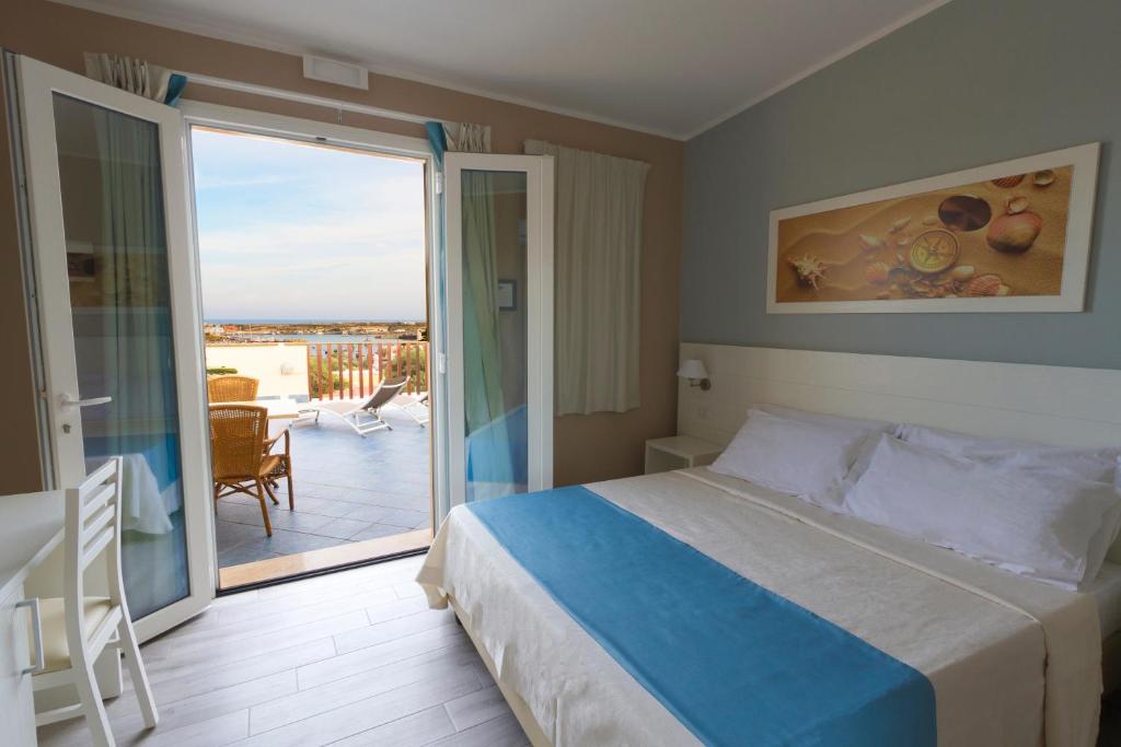 a bedroom with a bed and a balcony with a view at Le Anfore Hotel - Lampedusa in Lampedusa