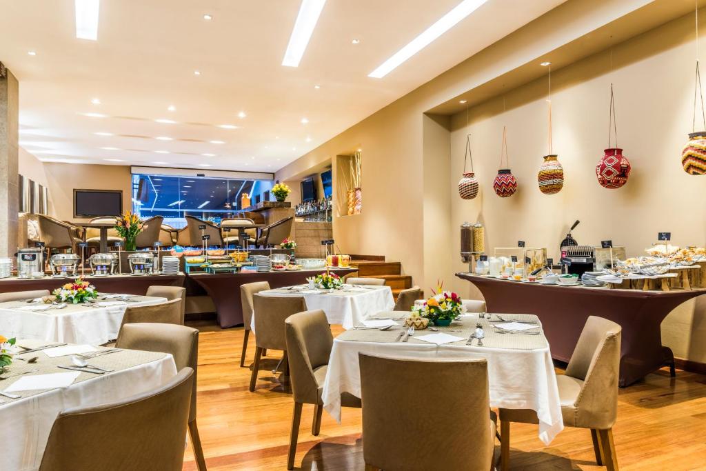 uma sala de jantar com mesas e cadeiras brancas em Hotel Rosales Plaza em Bogotá