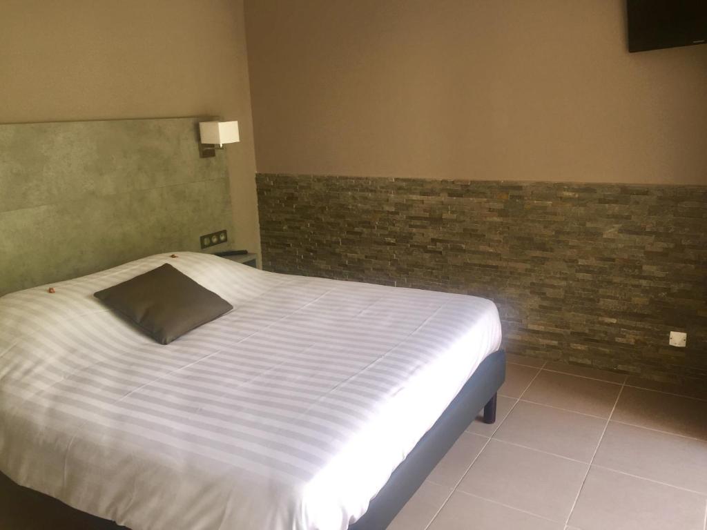 ein Schlafzimmer mit einem weißen Bett mit Ziegelwand in der Unterkunft Les Sarments in Le Lavandou