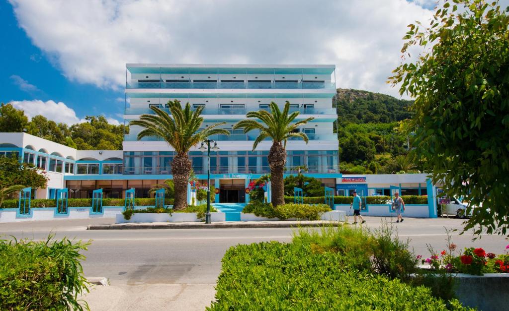 a blue building with palm trees in front of it at Belair Beach Hotel in Ixia