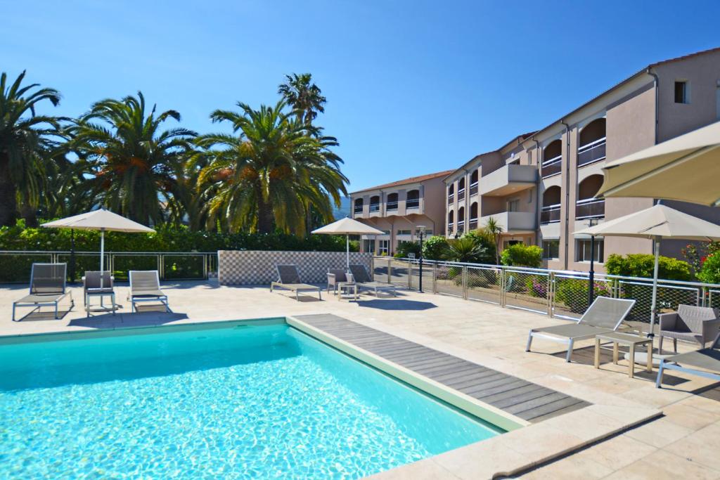 uma piscina com cadeiras e guarda-sóis ao lado de um edifício em Hotel Poretta em Lucciana