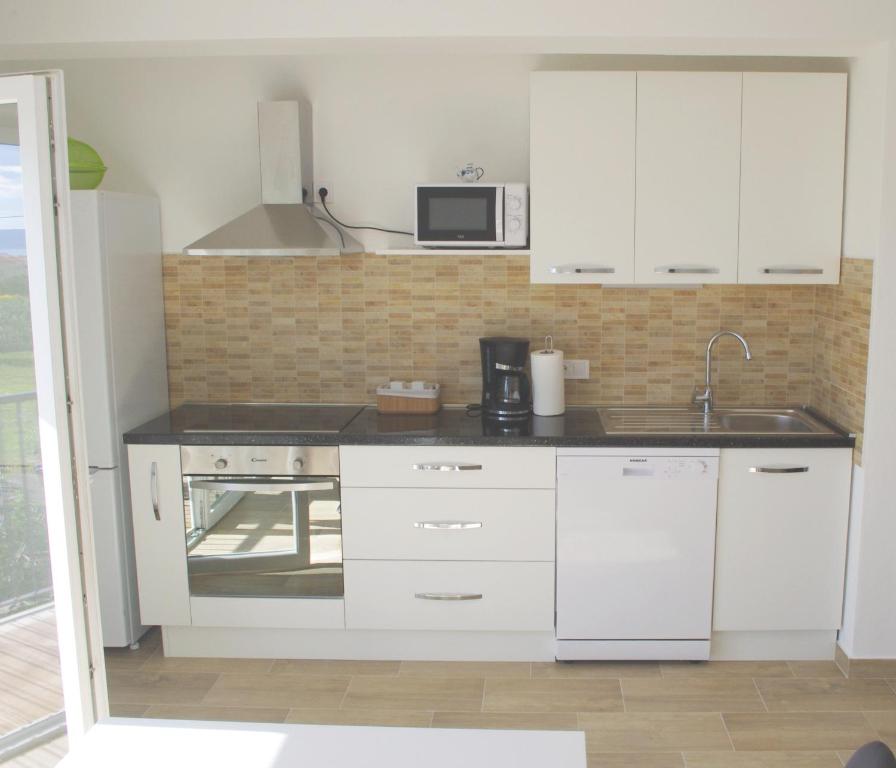 una cocina con armarios blancos y fregadero en Apartment LuMaGo en Kaštela