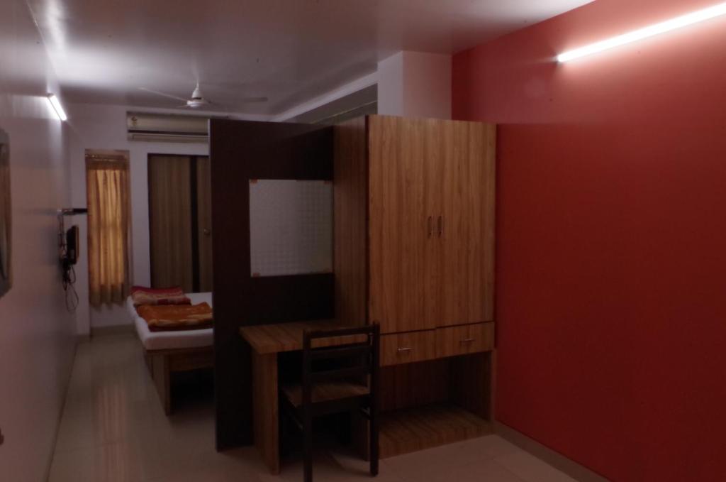 Habitación con mesa, silla y pared roja. en Hotel Pariwar en Aurangabad