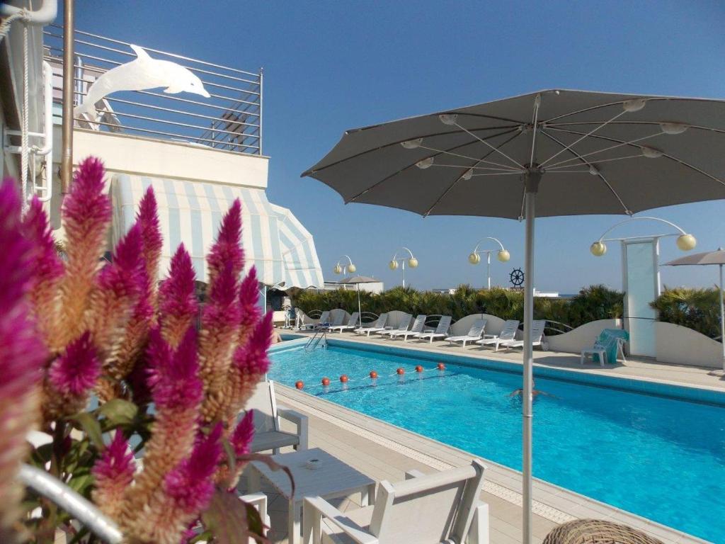 een zwembad met een parasol en stoelen en een zwembad bij Hotel Excelsior in Cesenatico