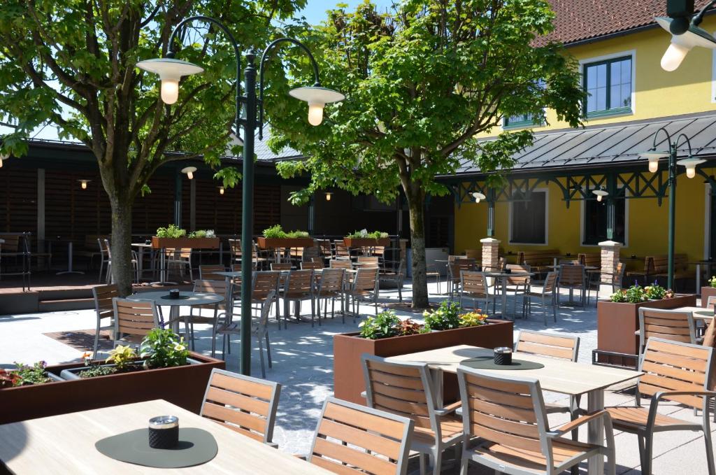 um pátio exterior com mesas, cadeiras e árvores em Thalinger Hof em Kronstorf