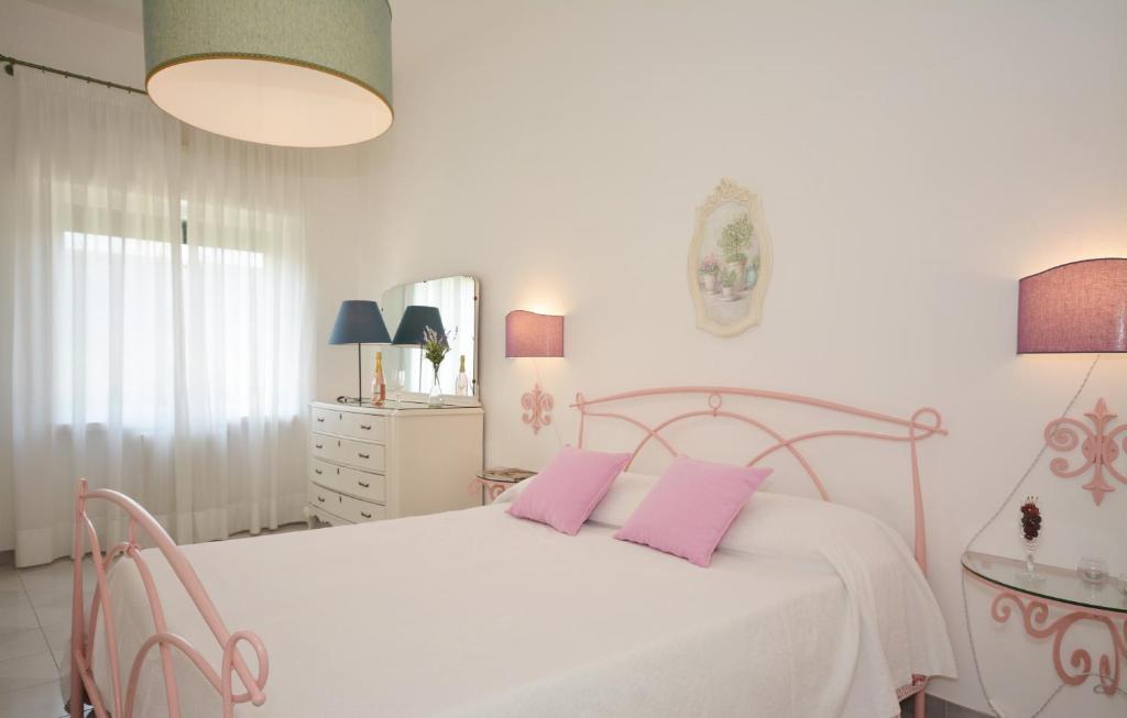 una camera bianca con letto bianco e cuscini rosa di LeccElite a Lecce