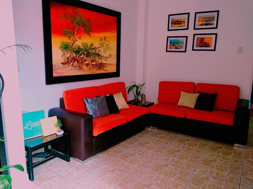 a living room with two red couches and a table at Hotel Kallma in Ica