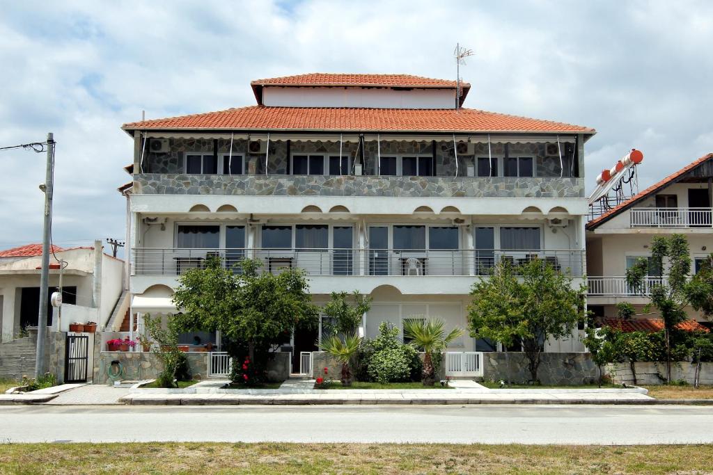 a large white building with a red roof at Ermioni Apartments in Nea Vrasna