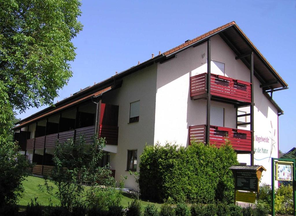 - un bâtiment blanc avec des balcons rouges sur le côté dans l'établissement Landhaus Vogelweide - 2 Zimmer mit Balkon, à Bad Füssing