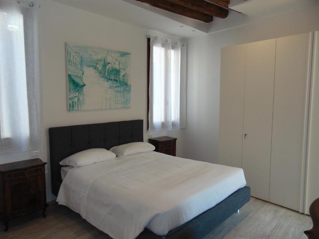 Un dormitorio con una gran cama blanca y una ventana. en Ca' Sansovino, en Venecia