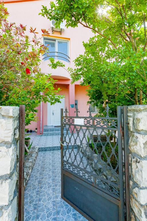 an open gate to a pink house with trees at Apartments Vanja in Bar