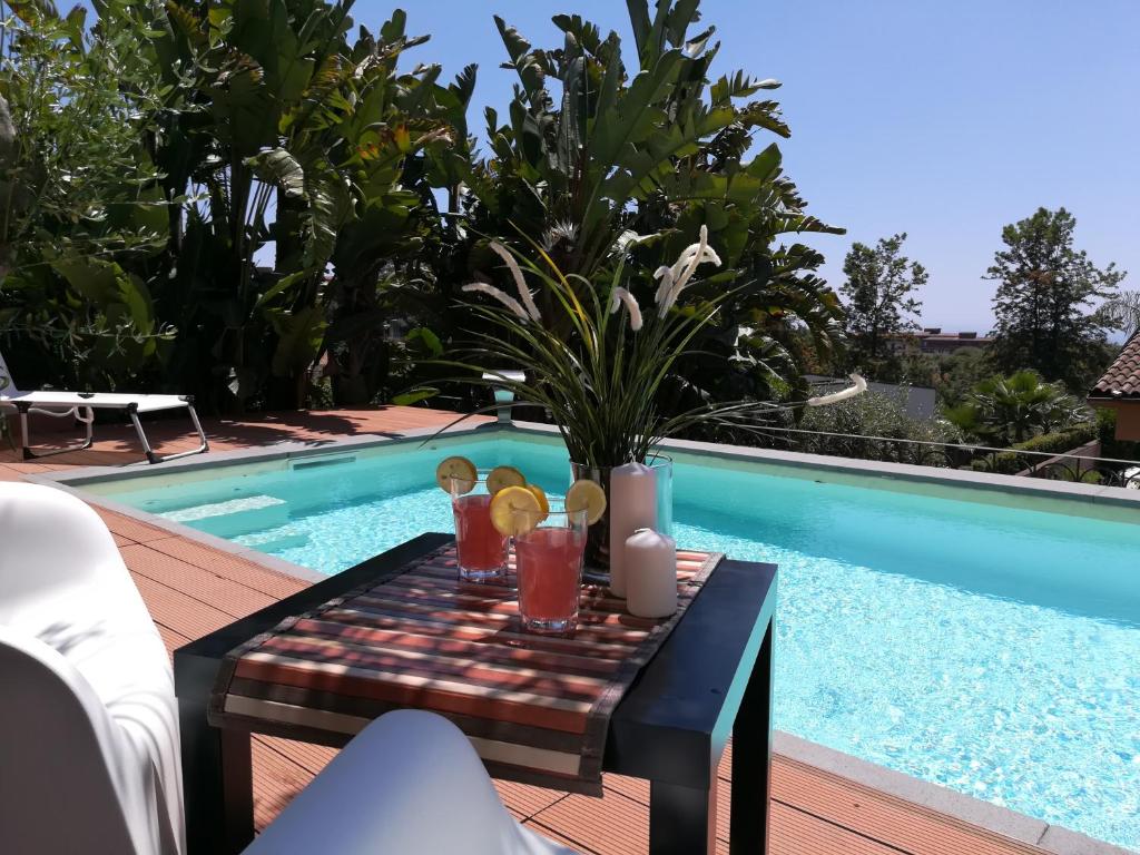 a table with drinks on it next to a swimming pool at Lily house in Gravina di Catania