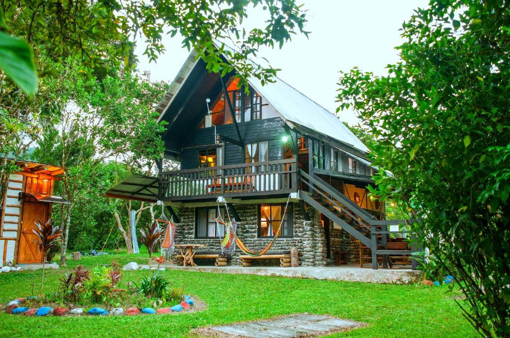 a large wooden house with a staircase in front of it at Casa de Piedra in Mindo