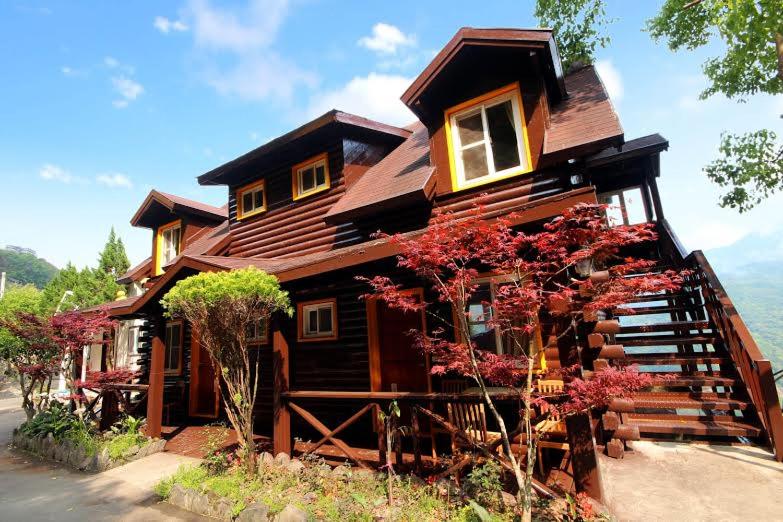 a large wooden house with flowers in front of it at La La Shan 5.5KNong Zhuang in Hualing