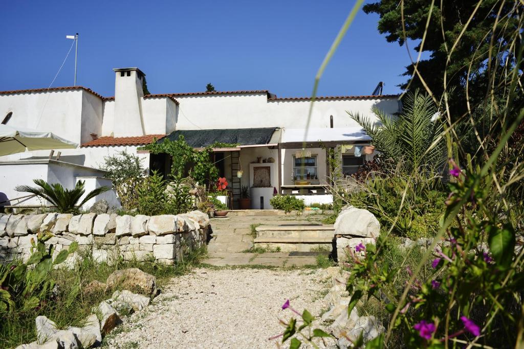 una casa bianca con un muro in pietra e un cortile di Mater Bed & Food-Riserva Naturale di Torre Guaceto a Serranova