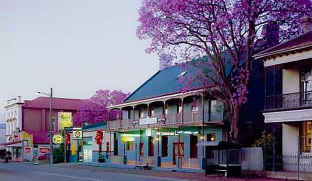 a town with purple trees and buildings on a street at Royal Hotel Singleton in Singleton