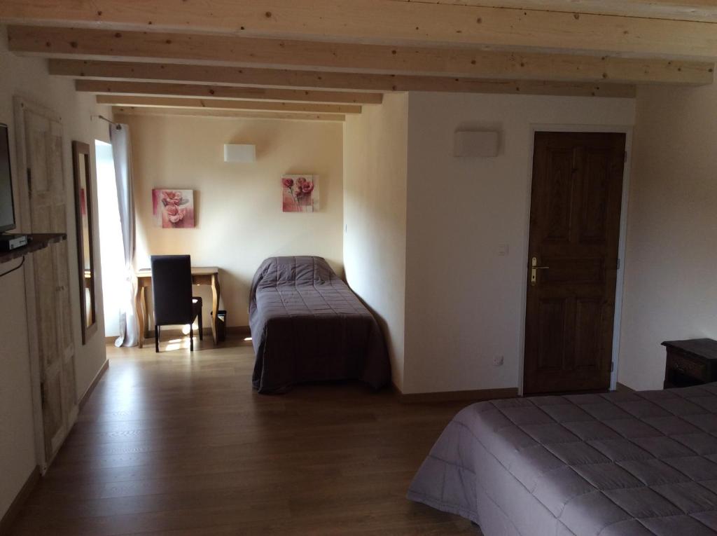 1 Schlafzimmer mit 2 Betten, einem Tisch und einem Stuhl in der Unterkunft Hotel Restaurant de la Poste in Aullène