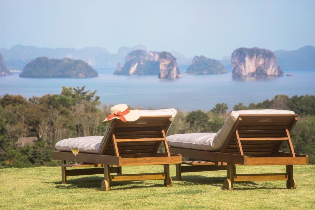 two lounge chairs sitting on top of a field with a lake at Koyao Island Resort in Ko Yao Noi