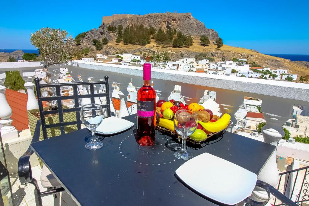 a table with a bottle of wine and a basket of fruit at Domna Studios in Lindos