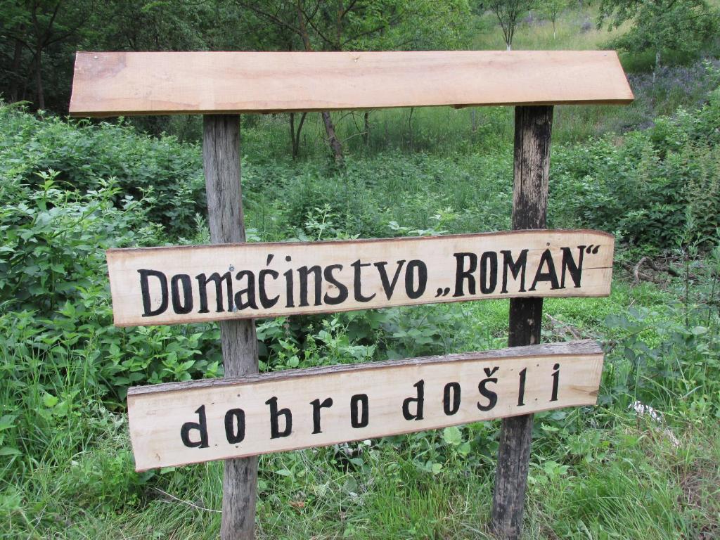 a wooden sign with two street signs on it at Country House Roman in Doboj