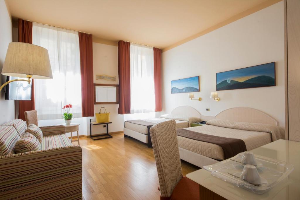a hotel room with two beds and a living room at Piazza Paradiso Accommodation in Siena