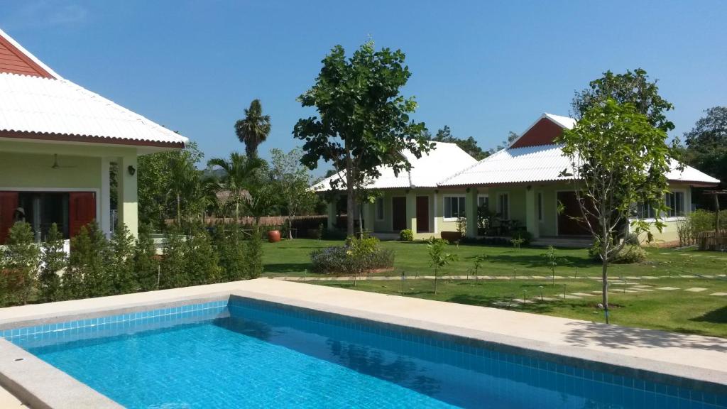 a villa with a swimming pool in front of a house at Ban Khan LeeMa in Sam Roi Yot