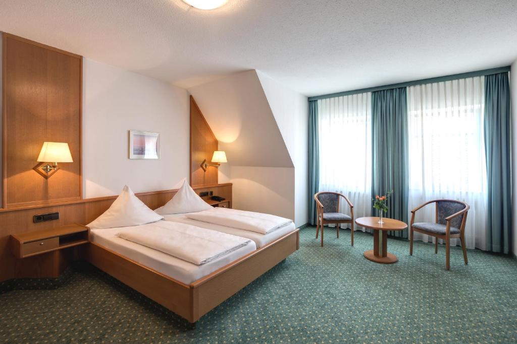 バート・メルゲントハイムにあるHotel-Gästehaus Alte Münzeのベッド、テーブル、椅子が備わるホテルルームです。