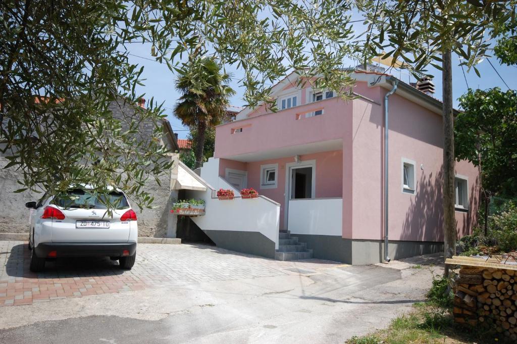 un coche aparcado frente a una casa rosa en Apartment Bazdaric en Sveti Vid-Miholjice
