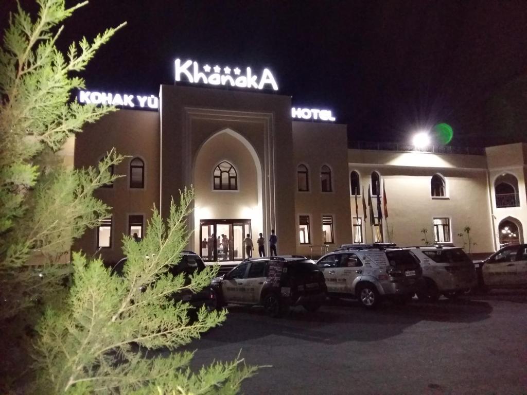 un edificio con coches aparcados delante de él por la noche en Hotel Khanaka, en Türkistan